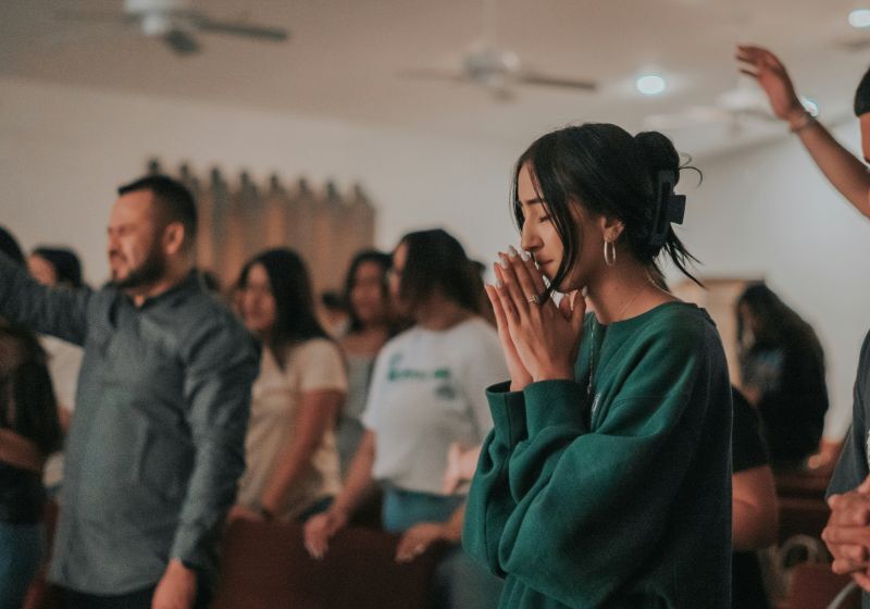 young woman eyes closed, praying during a full worship service