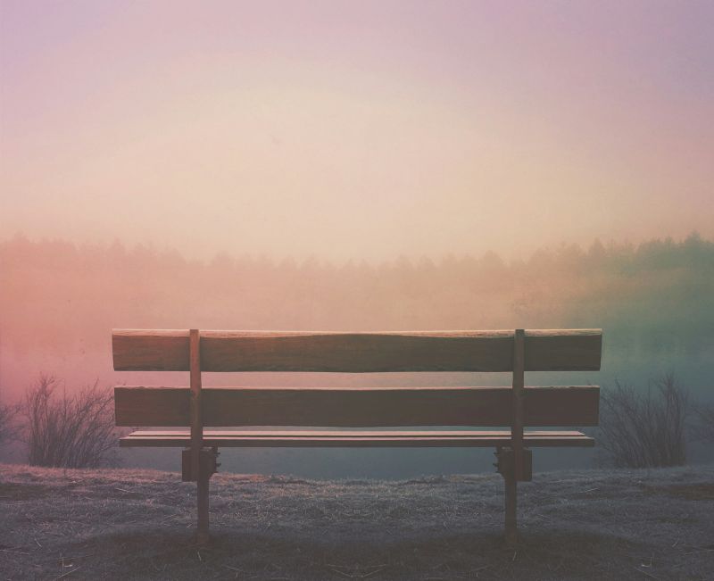 empty bench on mountain looking out at sunset