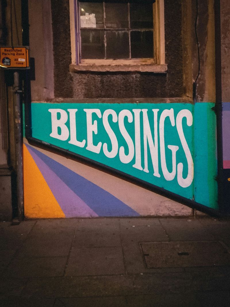 blessings on a sign white letters on green under a rustic window