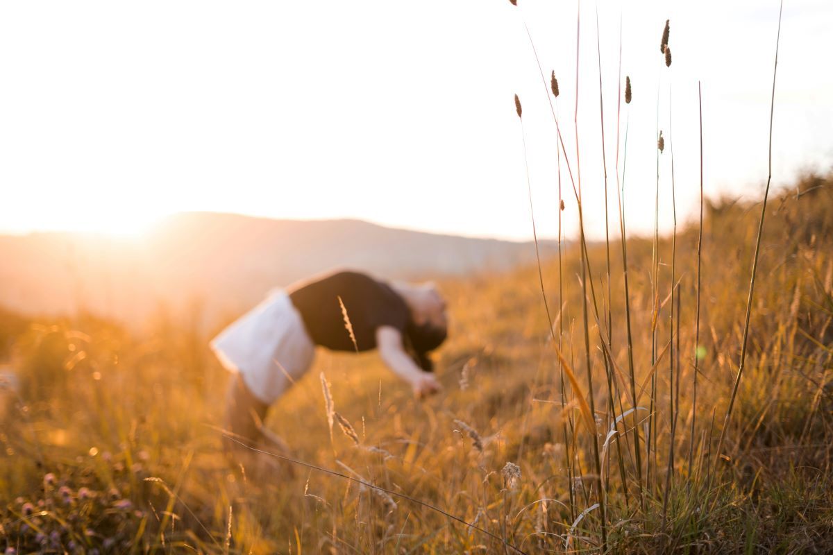 woman worshipping hands raised in field at sunrise