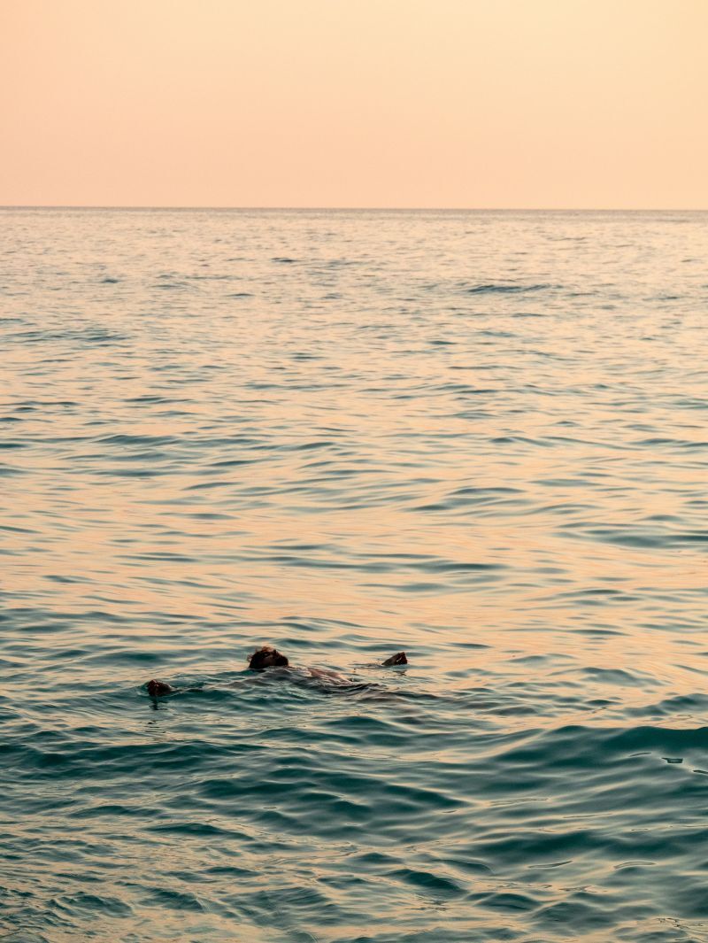Man floating on a lake at sunrise