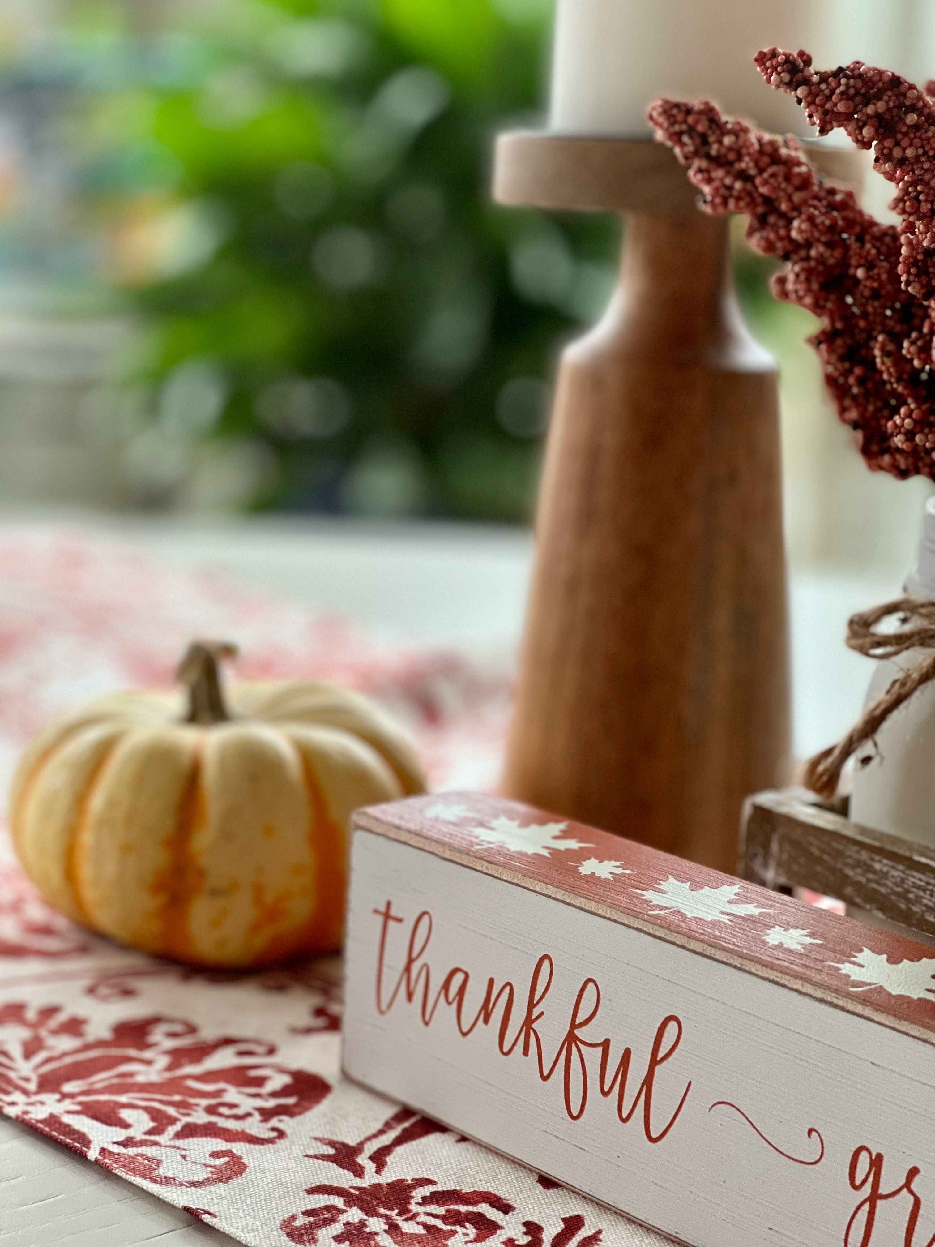 table set with pumpkins, candle and thankful sign