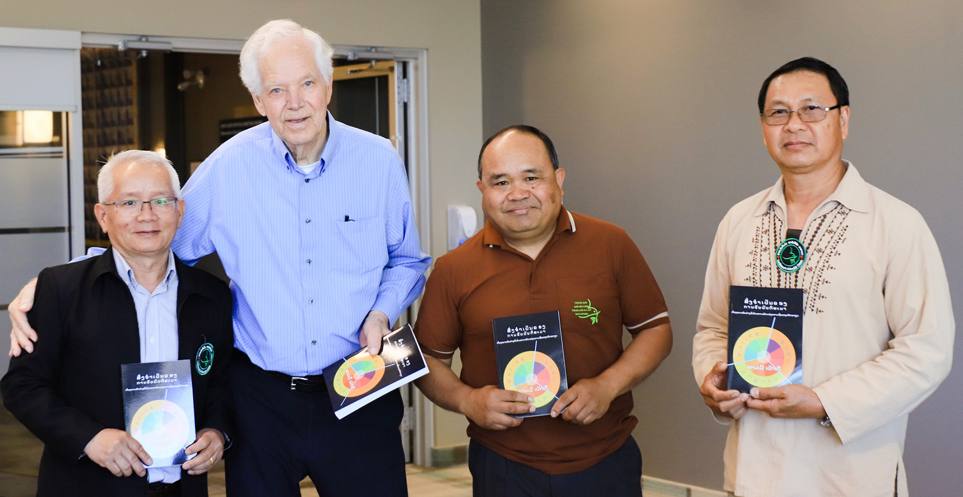 three Lao men and one White man with books in hands