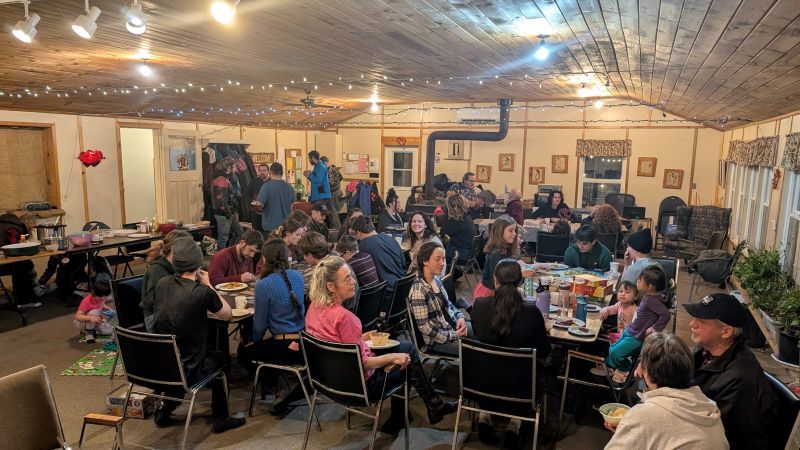 Large group of people gathered in a dining room talking and eating