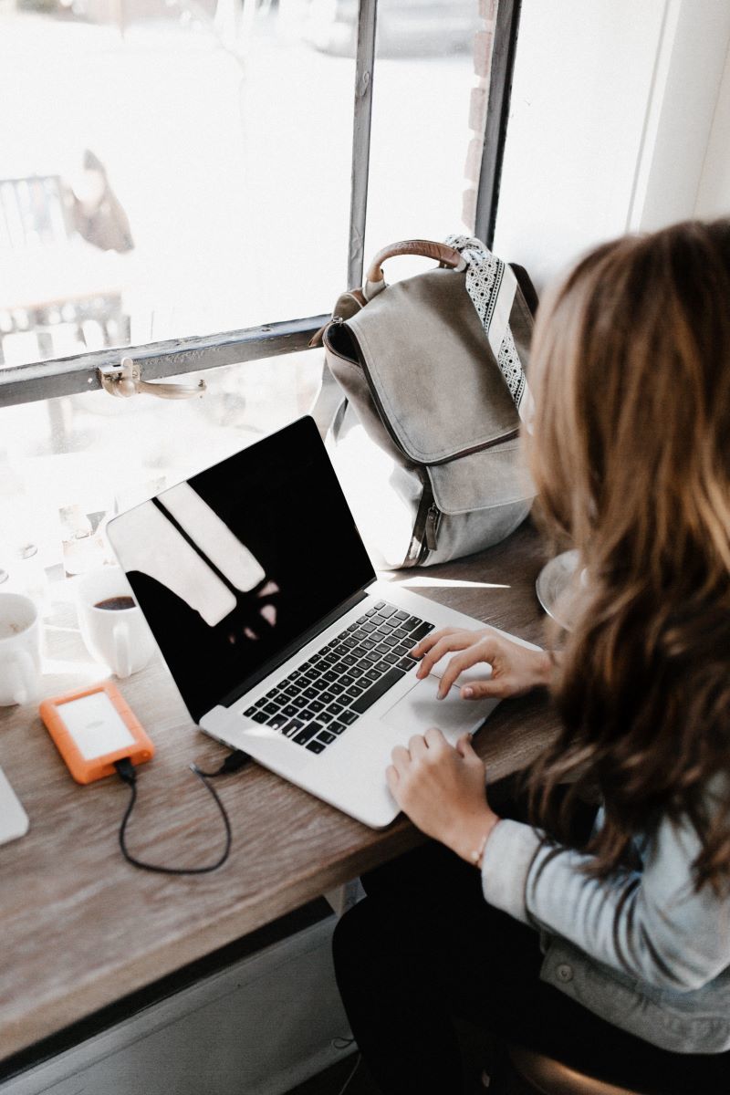 girl logging onto computer, knapsack in background