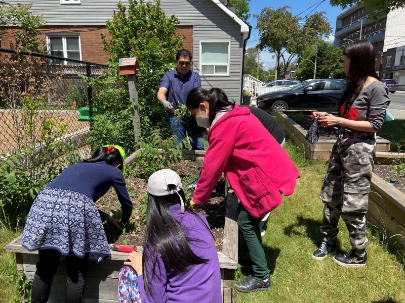 youth and adults planting a raised garden