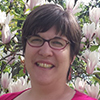 woman outside smiling at a blossoming tree