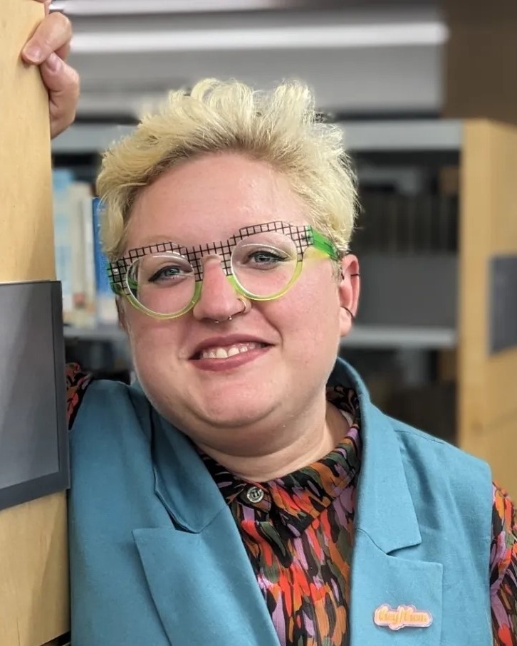 smiling person with blue vest and green glasses